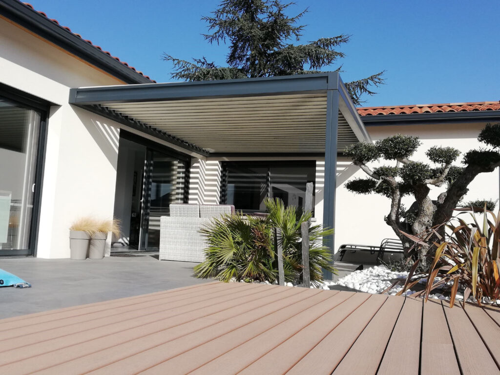 Terrasse moderne avec pergola bioclimatique, salon de jardin, deck bois, olivier, palmier et aménagement paysager.