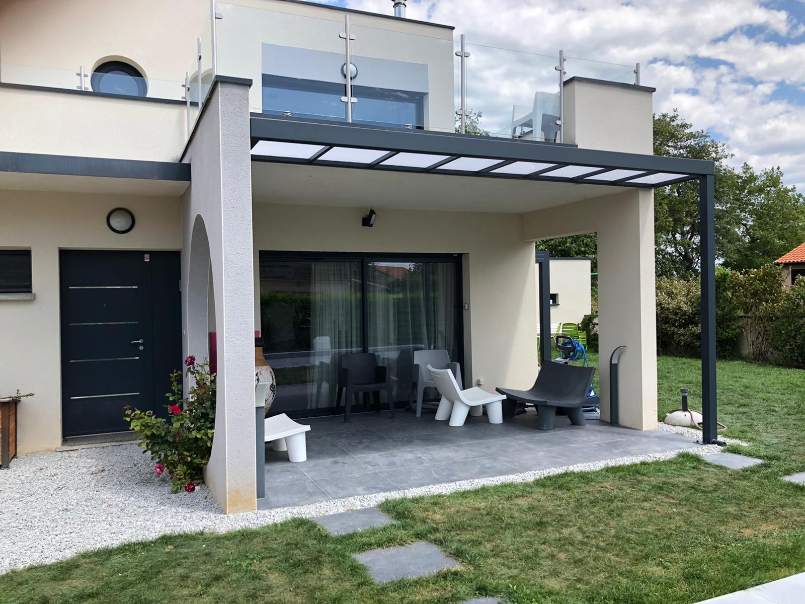 Terrasse de maison moderne avec pergola grise, mobilier design, jardin paysager et baie vitrée.