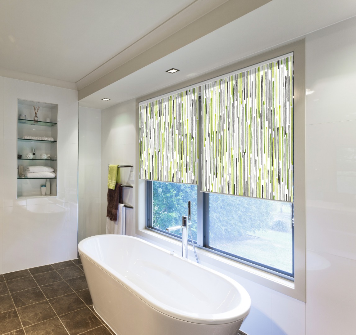 Salle de bain moderne avec baignoire, fenêtre et stores enrouleurs motif lignes verticales vertes et grises.