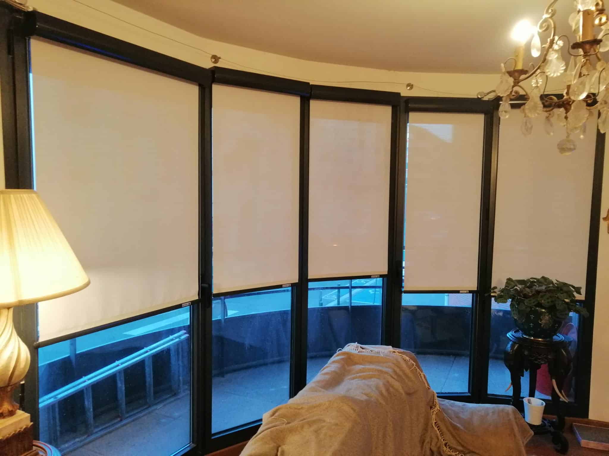 Intérieur avec quatre grandes fenêtres arquées, équipées de stores enrouleurs blancs baissés.