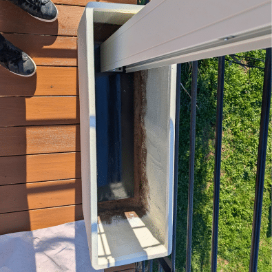 Pied de pergola bioclimatique lesté dans une grande jardinière sur terrasse bois.