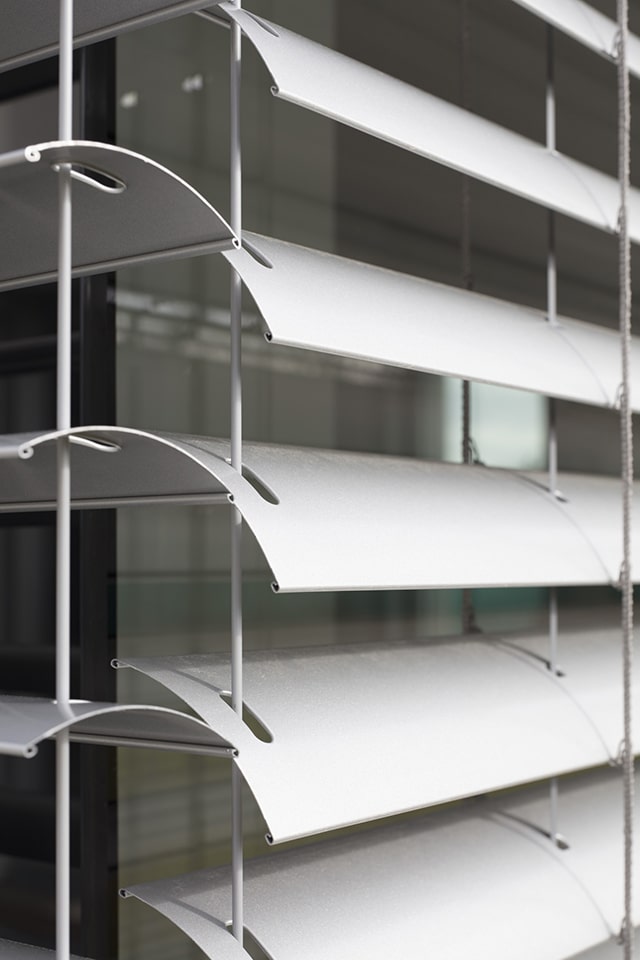 Zoom sur les lamelles en aluminium d'un brise-soleil orientable Solomatic argenté pour une façade design et moderne.